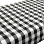 A table covered with a black and white checkered tablecloth, featuring a classic gingham pattern. The tablecloth has evenly spaced squares that create a timeless and rustic look.
