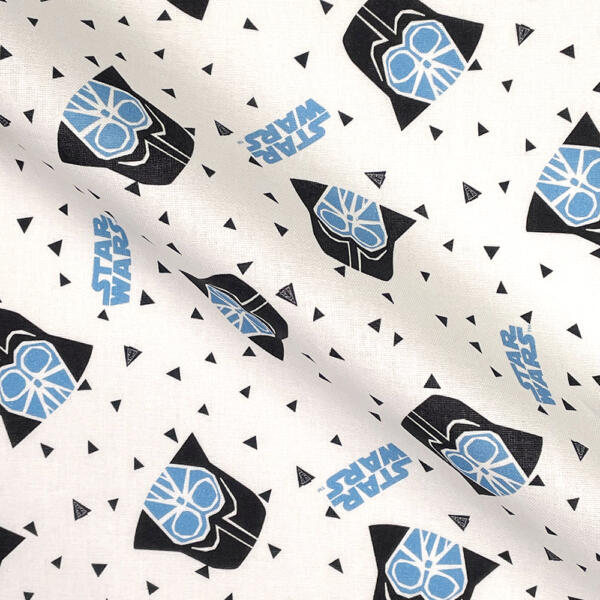 A white fabric featuring a pattern of black Darth Vader helmets with blue accents, "Star Wars" text in blue, and small black triangles scattered throughout. The fabric appears slightly wrinkled.