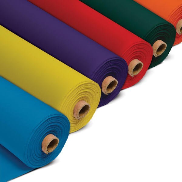 Rolls of cotton fabric, smoothly unrolled at one end to display its even and fine texture, tightly wound around a brown cardboard tube. The fabric colour is a vibrant blue, yellow, purple, red, green and orange