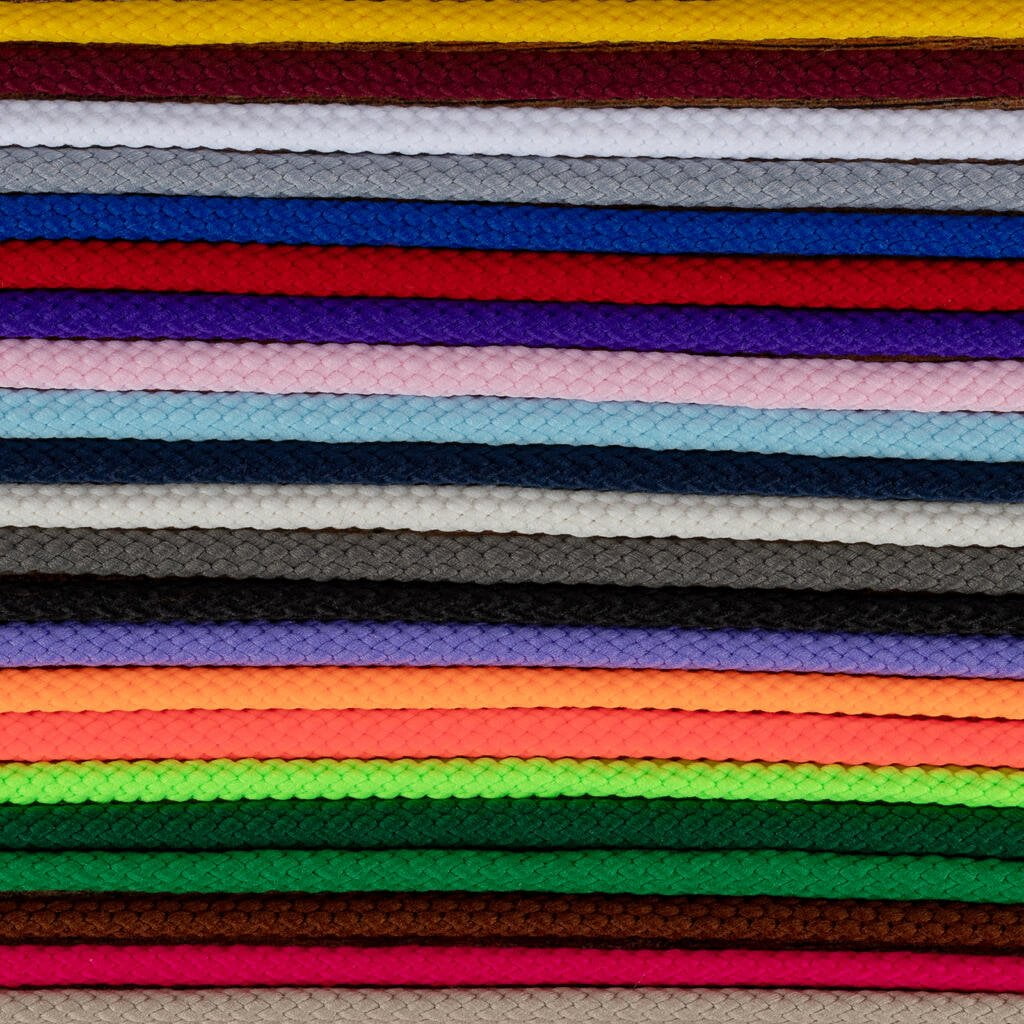 A stack of colorful braided cords arranged horizontally in rows. Colors include red, yellow, white, blue, purple, pink, black, gray, brown, green, orange, and more. Each cord's intricate braided pattern is visible, creating a textured and vibrant visual.