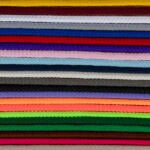 A stack of colorful braided cords arranged horizontally in rows. Colors include red, yellow, white, blue, purple, pink, black, gray, brown, green, orange, and more. Each cord's intricate braided pattern is visible, creating a textured and vibrant visual.