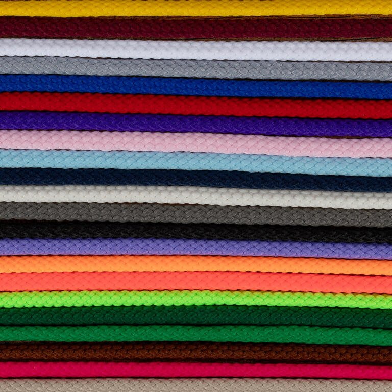 A stack of colorful braided cords arranged horizontally in rows. Colors include red, yellow, white, blue, purple, pink, black, gray, brown, green, orange, and more. Each cord's intricate braided pattern is visible, creating a textured and vibrant visual.