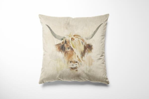 A square beige pillow features a watercolor-style painting of a highland cow with long horns and shaggy fur, predominantly in light brown and white tones. The cow's face is centered on the pillow, giving it a rustic and artistic look.