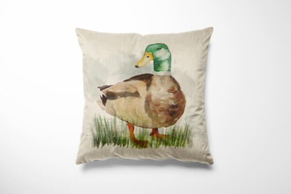 A square throw pillow with a watercolor illustration of a mallard duck standing on grass. The duck has a green head, yellow beak, and brown and white body. The pillow has a light beige background.