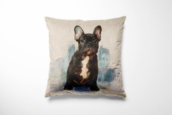 A decorative pillow featuring a print of a black French Bulldog with a white chest. The background has a subtle blend of blue and beige tones, giving a watercolor effect. The puppy has upright ears and a calm, attentive expression.