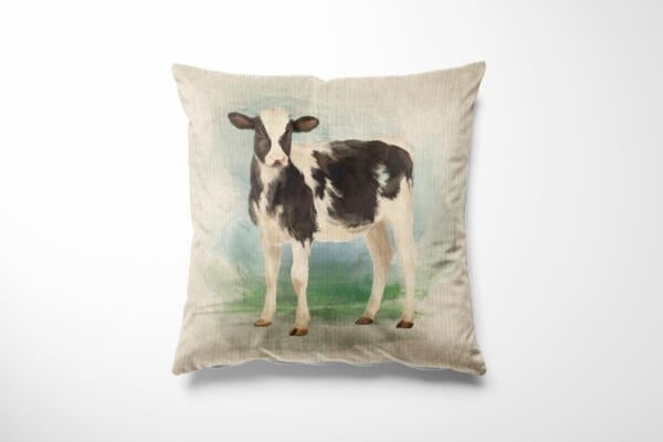 A square cushion with a printed image of a black and white calf standing on a green grassy background. The calf is centered on the beige fabric of the cushion. The design has a watercolor-like effect with soft, blended colors.