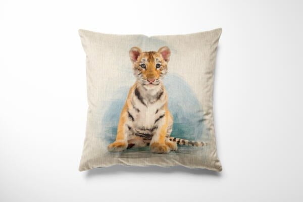 A square cushion with a light beige cover features a detailed, realistic print of a tiger cub sitting against a light blue and white background. The cub's fur is a mix of orange, white, and black stripes, conveying a cute and calm expression.