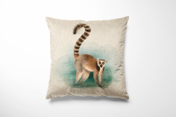 A decorative throw pillow with a light beige fabric featuring a detailed illustration of a ring-tailed lemur standing on a greenish-blue background. The lemur's tail is raised, showing its distinctive black and white stripes.
