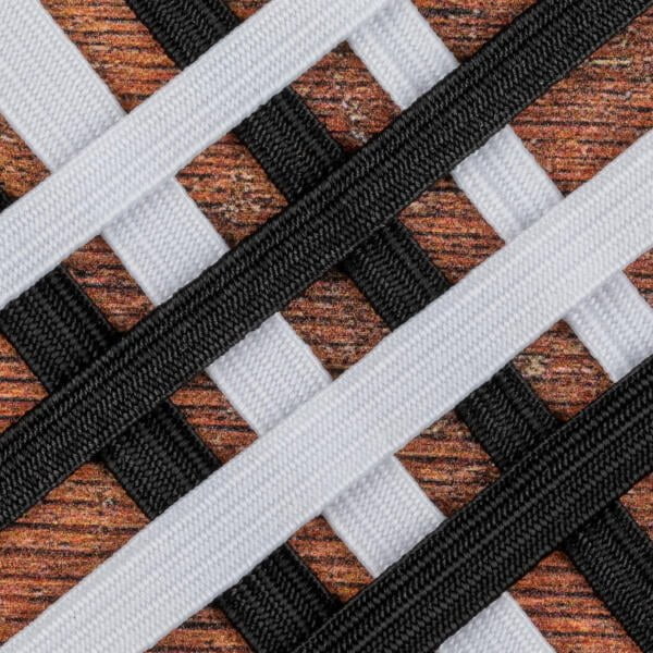 Close-up of a woven pattern consisting of intersecting black and white fabric strips forming a crisscross design against a textured orange-brown background. The strips alternate to create a checkered effect with a contrasting color scheme.