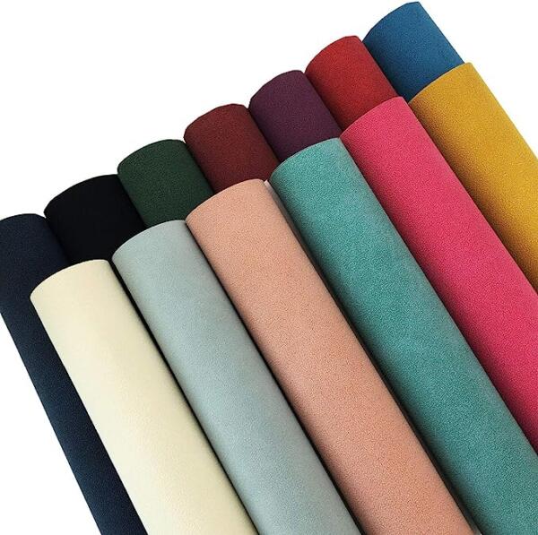 Nine rolls of fabric arranged vertically, each displaying a different color. The colors from left to right are dark blue, cream, pastel blue, light peach, rose pink, teal, burgundy, red, and golden yellow. The texture appears smooth and uniform.