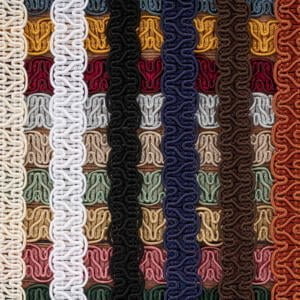 Close-up of intricately woven, colorful braided cords arranged vertically in rows. Each row features a different color, including white, yellow, red, green, black, blue, brown, and various other shades. The texture and patterns of the braids are prominent.