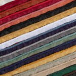 An array of colorful ribbons arranged horizontally. The ribbons display a variety of colors, including red, orange, pink, black, yellow, white, gray, green, and blue, with a decorative braided trim along one edge of each ribbon.