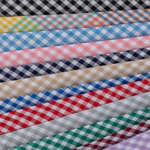 A stack of fabric rolls with a checkered pattern in various colors is arranged. The colors include black, yellow, turquoise, pink, blue, green, navy, beige, red, gray, and green. Each fabric has a white checkered pattern.