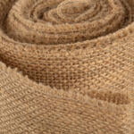 Close-up image of a rolled piece of brown burlap fabric, showing its coarse texture and weave pattern. The fibers appear rough and natural, with an organic and rustic look.