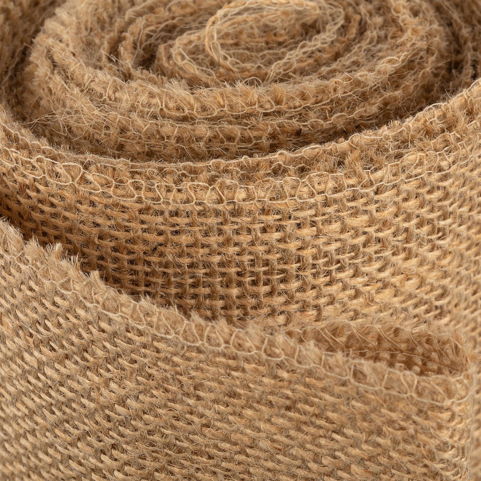 Close-up image of a rolled piece of brown burlap fabric, showing its coarse texture and weave pattern. The fibers appear rough and natural, with an organic and rustic look.