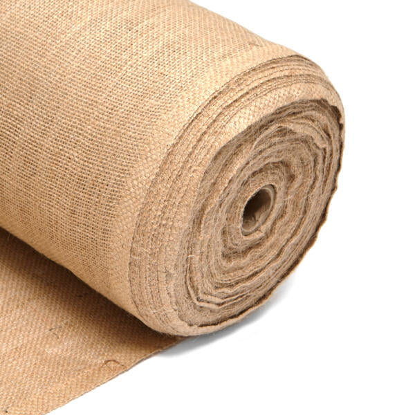 This image shows a roll of natural hessian fabric, also known as burlap. The fabric is tightly rolled into a cylindrical shape, displaying its coarse texture and beige colour. The roll rests on a similar hessian fabric, creating a seamless background that highlights the texture and natural weave of the material. The end of the fabric is slightly frayed, emphasising its rustic, organic quality. The colour is Natural