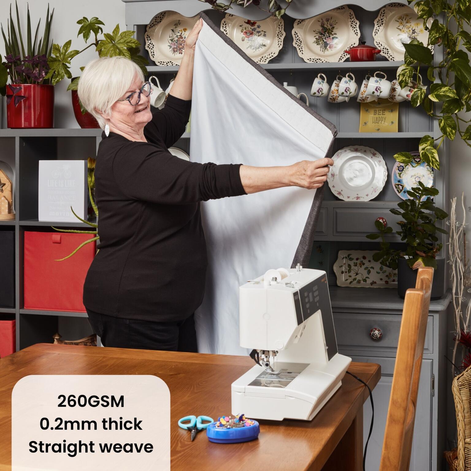 Blackout curtain lining fabric being shown by a home sewer who has completed her own homemade curtains using blackout curtain lining fabric and linen.