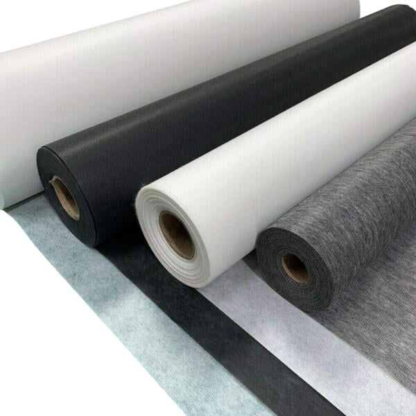 A close-up view of several rolls of fabric or non-woven material. The rolls are aligned horizontally, featuring a variety of colors including white, gray, and black. The edges of the fabrics are neatly cut, and the materials appear to be of different textures and thicknesses.