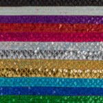 Rows of sequin fabric in various colors, including black, silver, purple, red, pink, white, gold, yellow, green, teal, and blue. The sequins create a sparkling effect, with each row showcasing a different vibrant hue.
