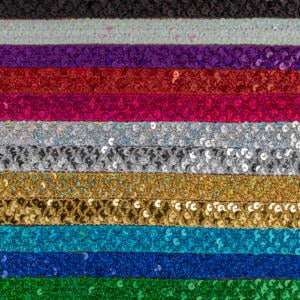 Rows of sequin fabric in various colors, including black, silver, purple, red, pink, white, gold, yellow, green, teal, and blue. The sequins create a sparkling effect, with each row showcasing a different vibrant hue.