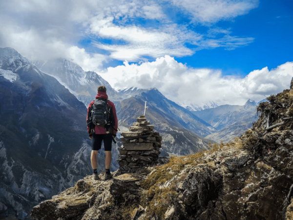 image of human on top of a mountain looking at the view. He's wearing outdoor fabrics and waterproof fabric.