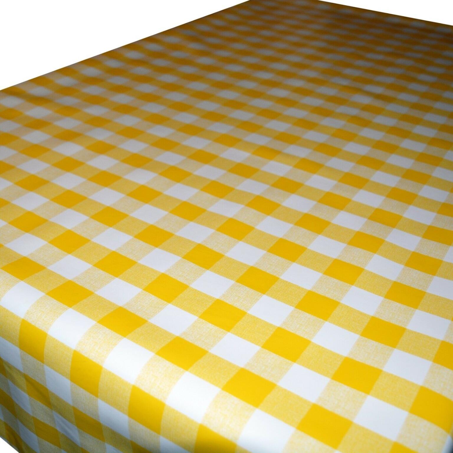 A table covered with a yellow and white checkered tablecloth featuring a classic gingham pattern. The tablecloth appears clean and neatly spread, with the checkered squares evenly aligned. The edge of the table is visible in the background.