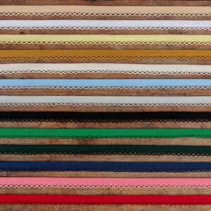 A collection of various colorful lace trims arranged in horizontal rows. The laces are in shades of brown, yellow, green, blue, pink, and other colors, each featuring intricate patterns and designs.