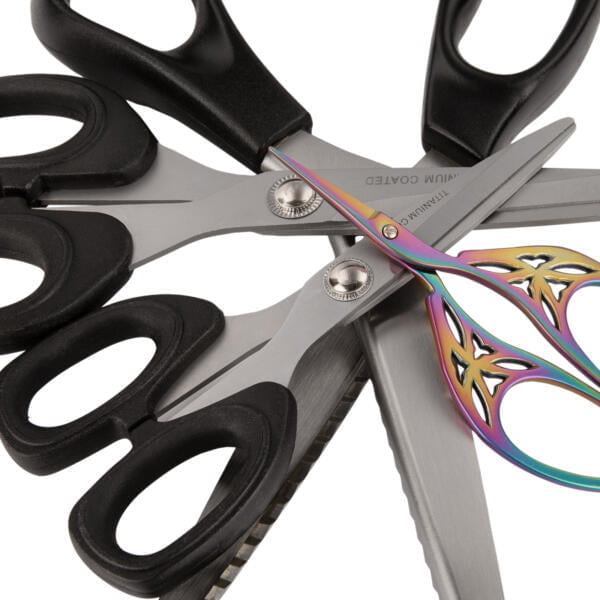 A collection of scissors arranged in a star-like pattern. The scissors have black handles except for one, which has a colorful handle with intricate designs. The blades are made of metal and some have unique patterns or serrations.