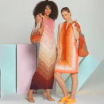 Two models pose in crochet dresses. The model on the left wears a long, multicolored dress with pink and orange hues and carries a matching shoulder bag. The model on the right wears a similarly styled sleeveless mini dress with orange and white tones and carries an orange bag.