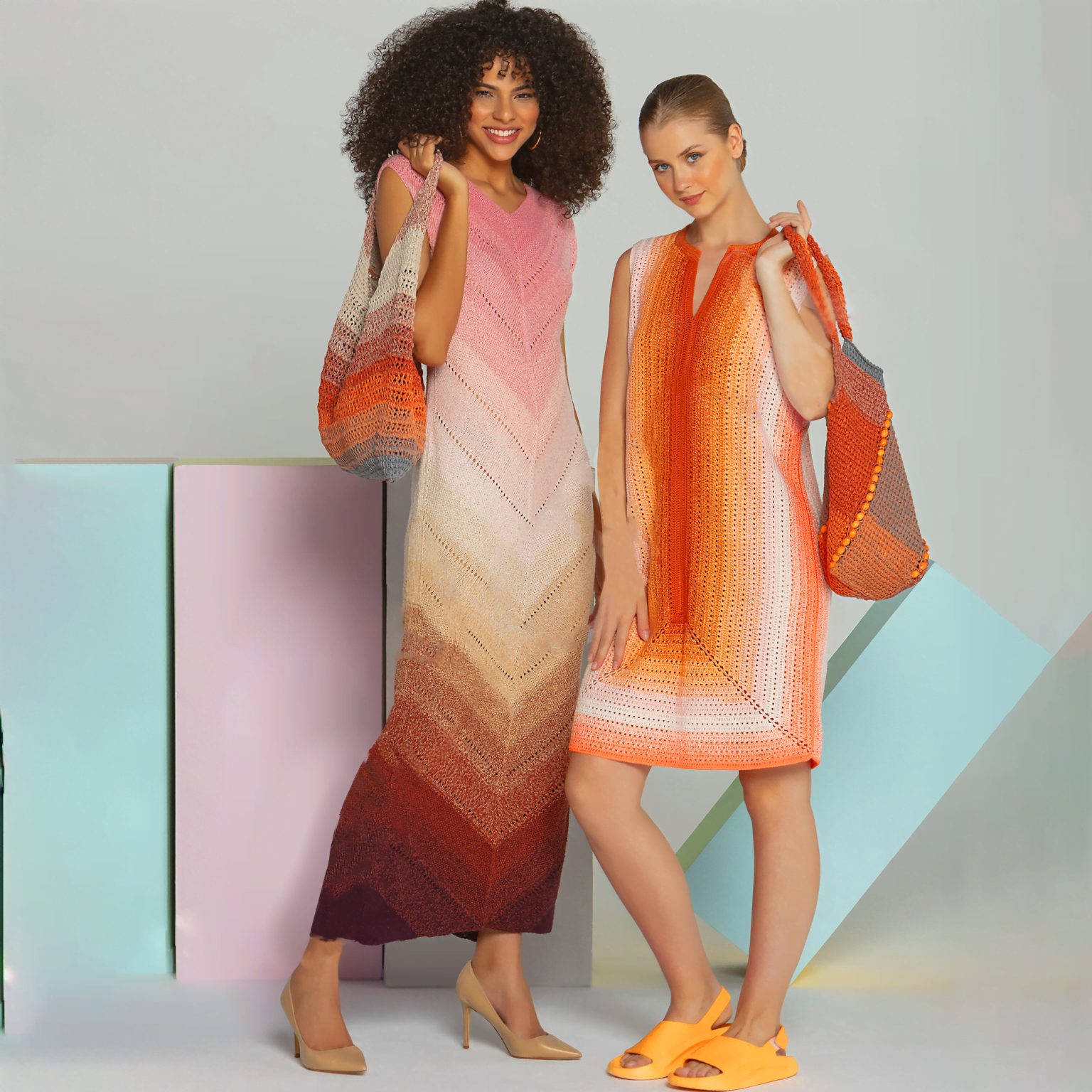 Two models pose in crochet dresses. The model on the left wears a long, multicolored dress with pink and orange hues and carries a matching shoulder bag. The model on the right wears a similarly styled sleeveless mini dress with orange and white tones and carries an orange bag.