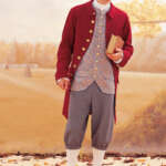 A person wearing 18th-century attire stands against a backdrop of autumn leaves. They are dressed in a red coat with gold buttons, a patterned waistcoat, grey breeches, white stockings, and black shoes with buckles. They hold a closed book and wear a tricorn hat.