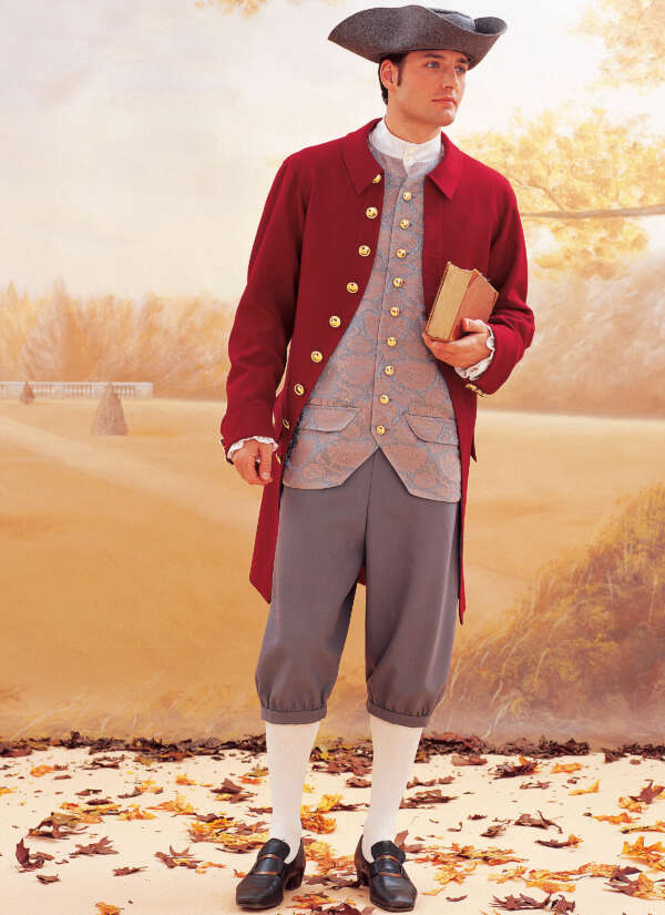 A person wearing 18th-century attire stands against a backdrop of autumn leaves. They are dressed in a red coat with gold buttons, a patterned waistcoat, grey breeches, white stockings, and black shoes with buckles. They hold a closed book and wear a tricorn hat.