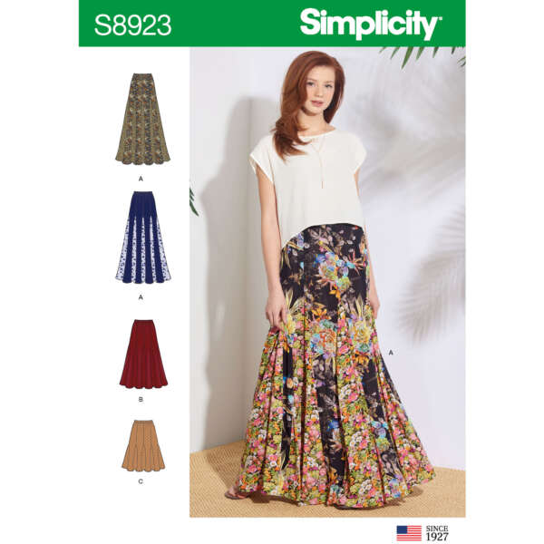 Image of a Simplicity sewing pattern S8923. The pattern features a long skirt in various fabric styles and colors, including floral prints and solid colors. A model wearing the floral print skirt and white top is displayed in the center. The American flag is in the bottom right corner.