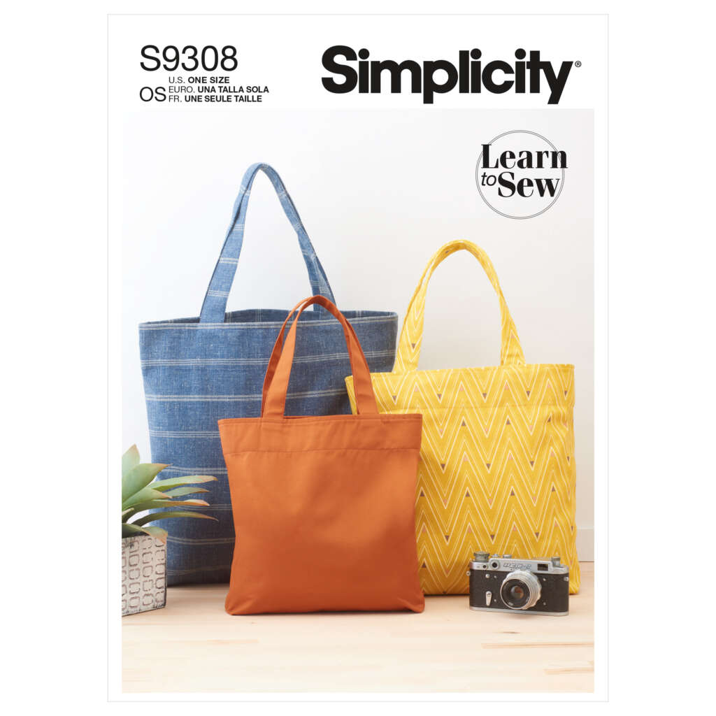 A Simplicity sewing pattern for making tote bags. The cover features three bags: a blue denim, an orange fabric, and a yellow zigzag-patterned one. A small potted plant and a vintage camera are placed in the foreground. Text reads "S9308" and "Learn to Sew.