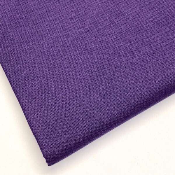 Close-up of a piece of purple fabric with a smooth texture, neatly folded at the corner, placed against a plain white background.