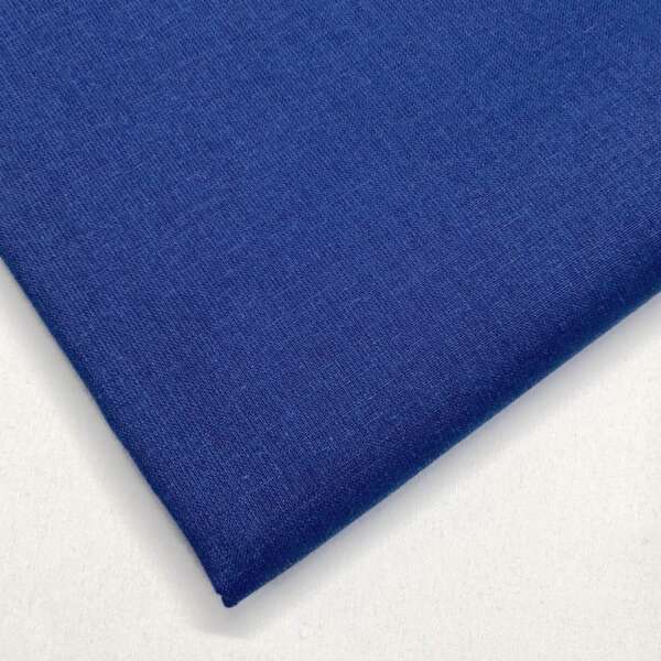 A close-up shot of a neatly folded piece of deep blue fabric with fine texture. The fabric is displayed against a white background, showcasing its smooth and uniform surface.