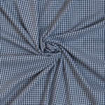 A piece of blue and white gingham fabric is tightly gathered and twisted into a circular pattern in the center, creating radiating folds. The checkered pattern is consistent throughout, giving a neat and uniform appearance.