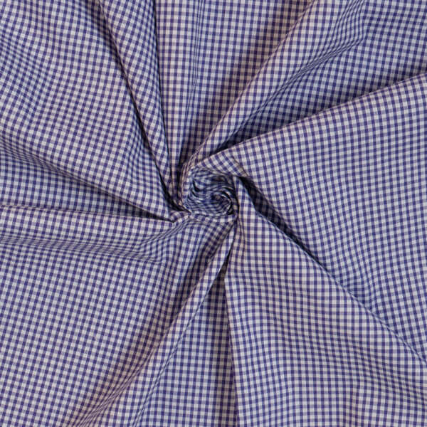 A close-up image of a twisted piece of fabric with a small blue and white gingham check pattern. The twisting of the fabric creates a star-like design in the center, showcasing the texture and pattern of the material.