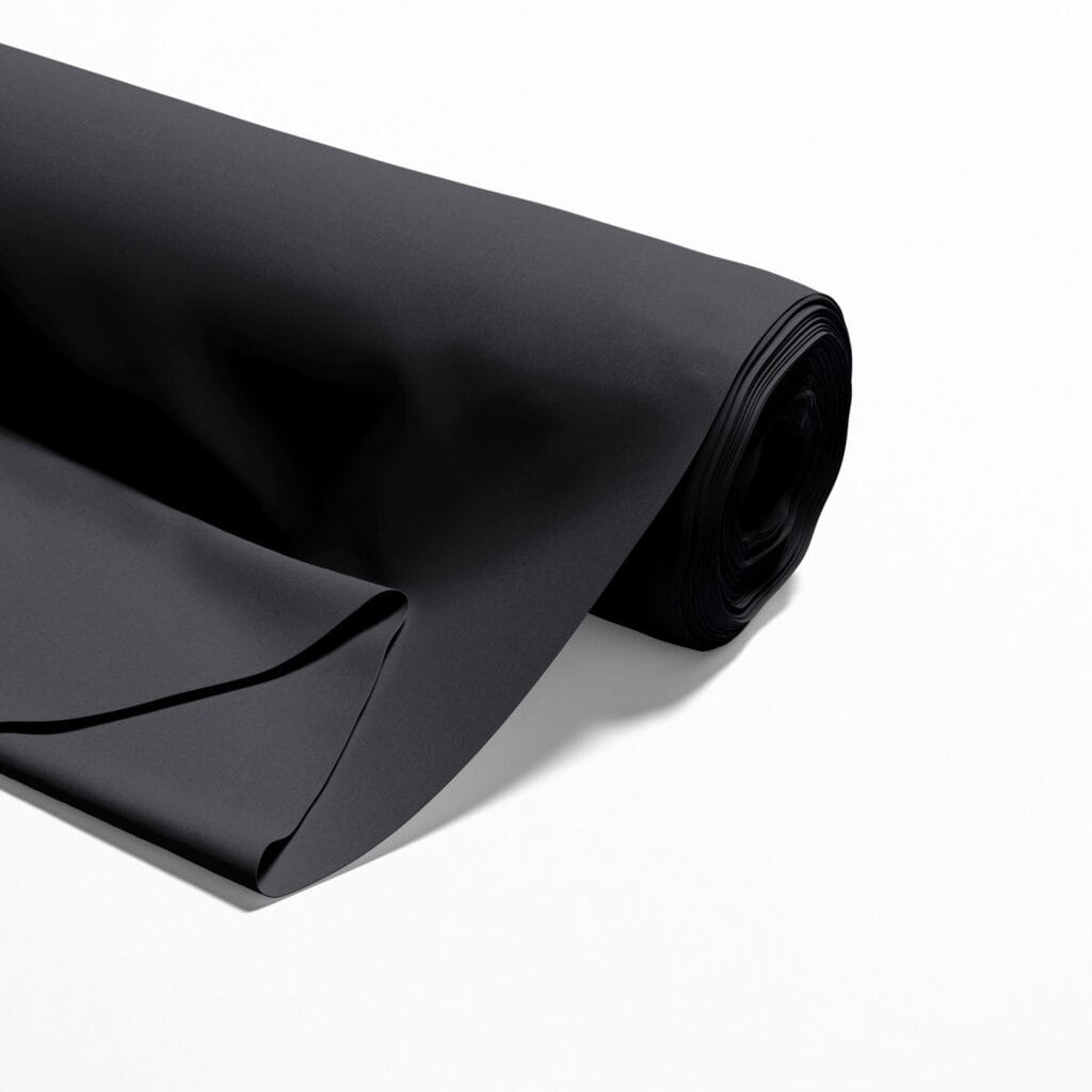 A roll of black fabric partially unrolled on a white surface. The fabric appears smooth and has a matte finish, with clean edges and a slight sheen.