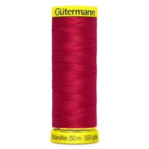 A spool of Gütermann Maraflex thread in red, featuring a yellow top and bottom with labels. The spool reads "150 m - 165 yds.