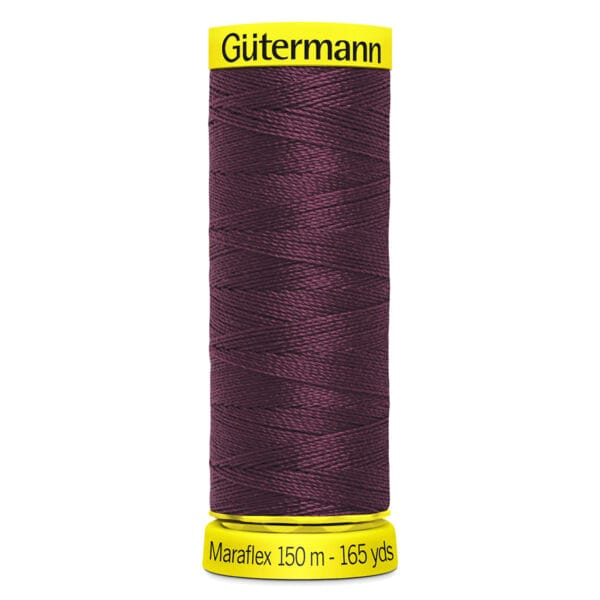 A spool of Gütermann Maraflex sewing thread in maroon is displayed. The spool has a bright yellow base and top. It contains 150 meters (165 yards) of thread.