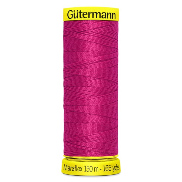 A spool of Gütermann Maraflex thread in bright pink, with "150 m - 165 yds" labeled on the bottom. The spool has yellow end caps with the brand name on top.