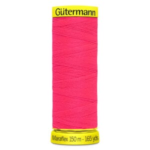 A spool of Gütermann Maraflex thread in bright pink, with yellow caps on both ends. The top cap reads "Gütermann," and the bottom cap states "Maraflex 150 m - 165 yds.