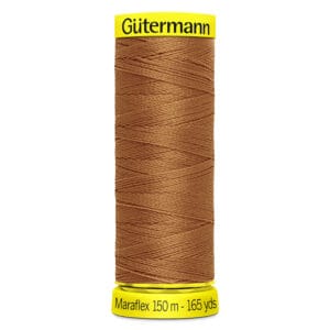 A spool of Gütermann Maraflex thread in brown, labeled with "150 m - 165 yds" on a yellow base. The brand name is on a yellow top section. The thread is wound tightly in a crisscross pattern.