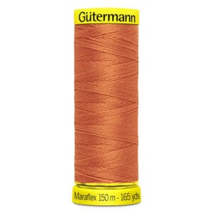 Spool of Gütermann Maraflex thread, 150 meters (165 yards) in length. The thread is a warm, rust color. The spool has bright yellow ends with the brand and thread details printed in black.