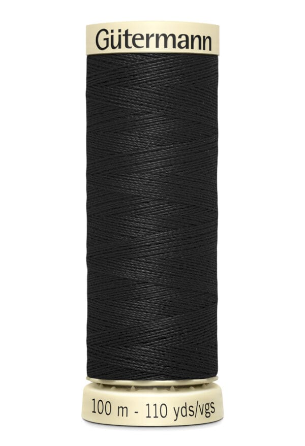 A spool of Gütermann black sewing thread labeled "100 m - 110 yds/vgs." The label and spool ends are cream-colored, providing contrast with the dark thread.