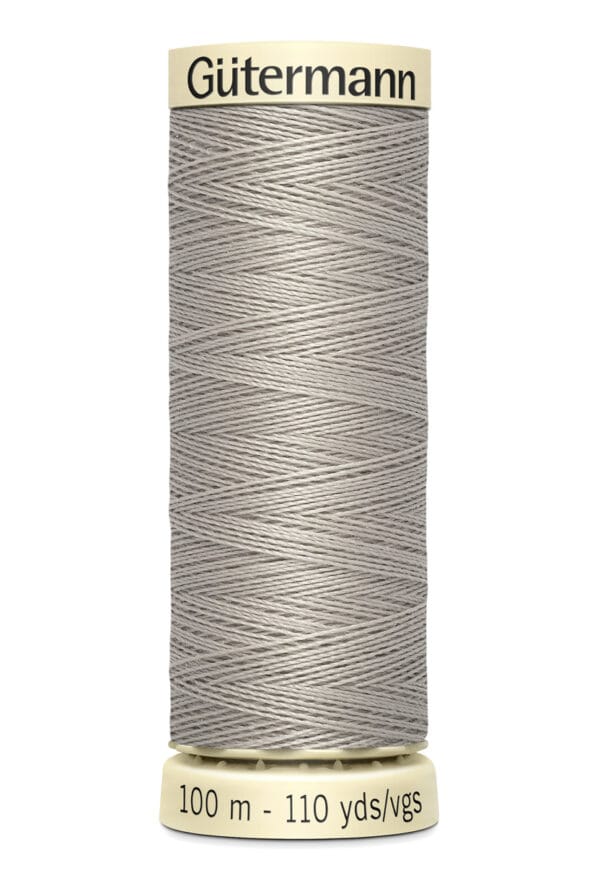 A spool of gray Gütermann sewing thread, labeled with "100 m - 110 yds/vgs" on the base. The spool has a beige top and bottom.