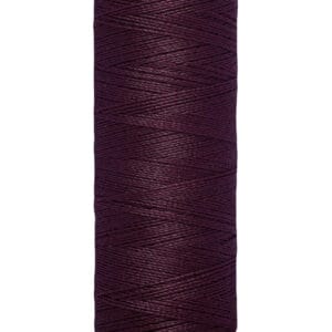 A spool of Gütermann thread, deep purple in color, labeled with "100 m - 110 yds/vgs" on the beige base.