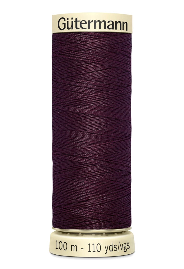 A spool of Gütermann thread, deep purple in color, labeled with "100 m - 110 yds/vgs" on the beige base.