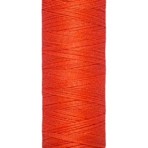 A spool of Gütermann red sewing thread, with cream-colored ends. The label indicates the length as 100 meters or 110 yards. The thread is tightly wound around the spool.